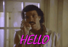 a man with a mustache is talking on a phone and saying `` hello '' .