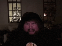 a man with a beard is wearing a hoodie in front of a christmas tree ..