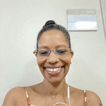 a woman wearing glasses and ear buds smiles in front of a sign that says 404