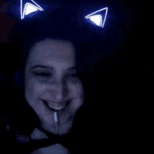 a woman with cat ears on her head smiles in the dark