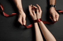 a man and woman are tied up with red ribbons .