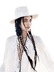 a woman wearing a white hat and a white dress with braids in her hair .