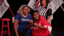 two women are posing for a picture with one wearing a blue shirt that says ' chicago olympics ' on the front