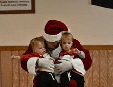 a man in a santa suit is holding two little boys in front of a sign that says justice freedom and democracy