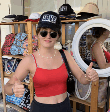 a woman wearing a hat that says love on it giving a thumbs up