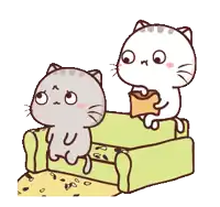 two cats are sitting on a green couch and one is holding a purse