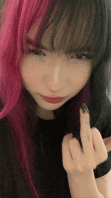 a girl with pink and black hair gives the middle finger