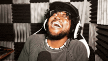 a man wearing glasses and headphones is laughing with his mouth open