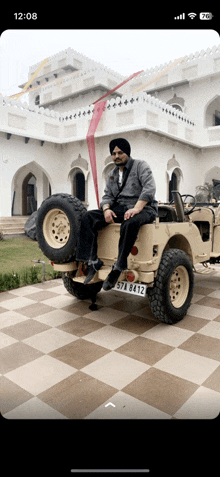 a man in a turban is sitting on the back of a jeep with a license plate that says 574 8412