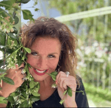 a woman with a ring on her finger is smiling while holding flowers in her mouth