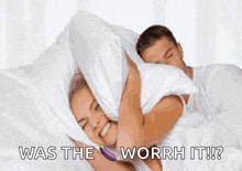 a man and a woman are laying in bed with a pillow over their heads and the woman is holding an eggplant .