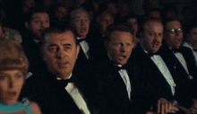 a group of men in tuxedos sit in a dark room