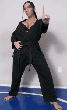 a woman in a black karate uniform points her finger