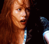 a close up of a woman 's face with long red hair