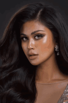 a close up of a woman 's face with long dark hair and earrings