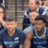 two grizzlies basketball players are sitting in the stands
