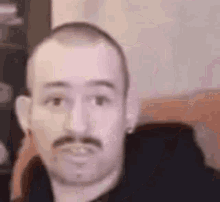 a man with a mustache and earrings is making a funny face in a blurry photo .