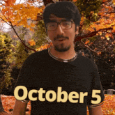 a man wearing glasses and a black shirt that says october 5 on it