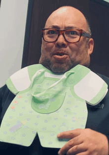 a man wearing glasses is holding a baby bib that says ' world ' on it