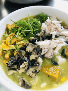 a white bowl filled with a green soup with meat and vegetables