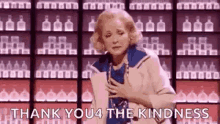 a woman is standing in front of a shelf of bottles and saying `` thank you for the kindness '' .