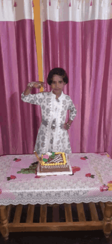 a little girl is standing in front of a birthday cake on a table