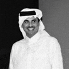 a black and white photo of a man wearing a head scarf and a white shirt .