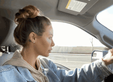 a woman driving a car with a sun visor that says warning