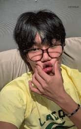 a young man wearing glasses and a yellow shirt that says lasq