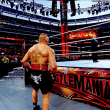 a man is standing in a wrestling ring in front of a sign that says ' wrestling ' on it