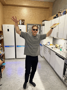 a man wearing sunglasses and a mustache is holding a plate in a kitchen