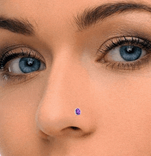 a close up of a woman 's nose with a purple stone in it .