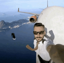 a man taking a selfie in front of a plane