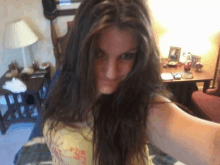 a woman taking a selfie in a living room with a table and chairs in the background