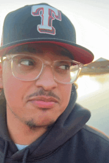 a man wearing glasses and a hat with a t on it