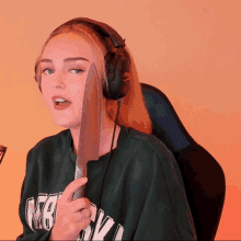 a woman wearing headphones is holding a large knife in front of her face