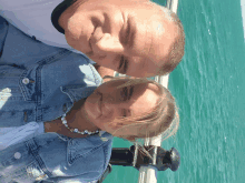 a man and a woman are posing for a picture with the water in the background