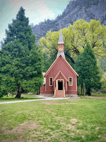 a small red church is surrounded by trees and mountains