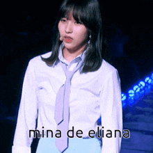 a woman wearing a white shirt and a purple tie with mina de eliana written on the bottom right