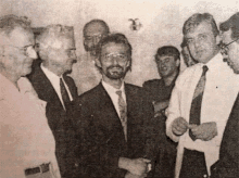 a group of men in suits and ties are standing in a room