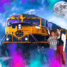 two women pose in front of a yellow train with the number 4324