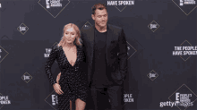 a man and a woman pose for a photo in front of a wall that says people 's choice awards