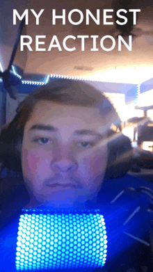 a man with headphones and a blue light behind him with the words my honest reaction