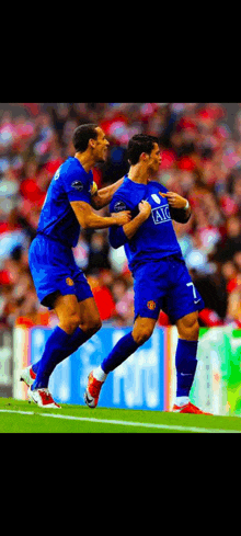 two soccer players wearing blue jerseys with the letters aig on the front