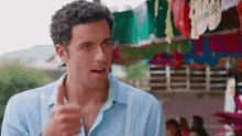 a man in a blue shirt is giving a thumbs up sign while standing in front of a carnival .