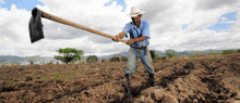 a man in a cowboy hat is digging in a field