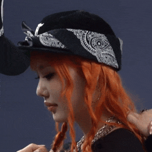 a woman with red hair is wearing a bandana and a baseball cap