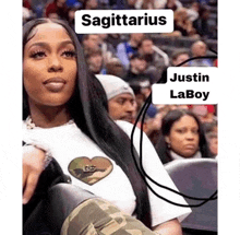 a sagittarius woman is sitting in a stadium with justin laboy behind her .