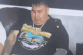 a man is sitting in a chair wearing a t-shirt with a picture of a shark on it .