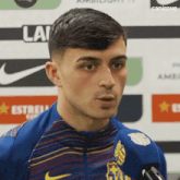 a young man is talking into a microphone while wearing a striped jersey .